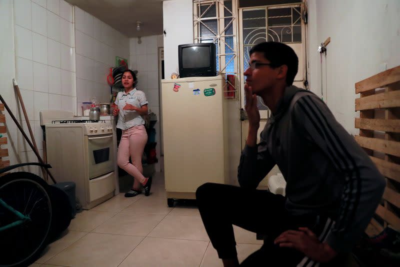 Diego Alvarez gestures near his girlfriend Jetsymar Torres from Venezuela chat at their house in Bogota