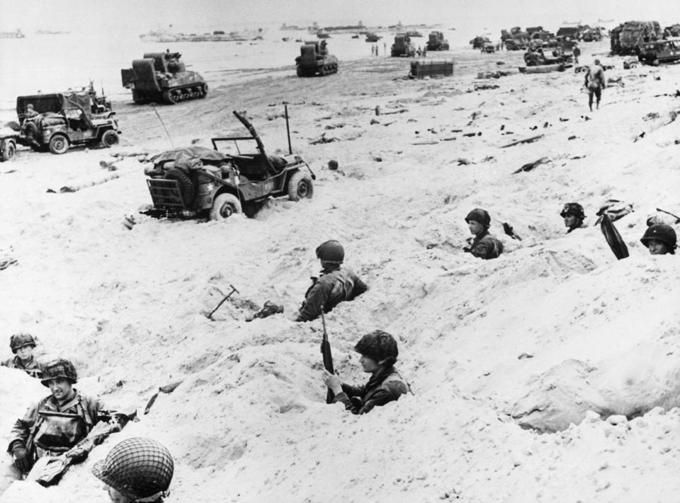 American soldiers wait in foxholes at Utah Beach on D-Day for the order to move inland against German fortifications.