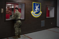 In this June 17, 2020, photo made available by the U.S. Air Force, a member of security forces stands at the 316th Security Support Squadron armory window to receive weapons and equipment for his shift at Joint Base Andrews, Md. Using government records covering the Army, Marines, Navy and Air Force, an Associated Press investigation showed that military pistols, machine guns, shotguns and assault rifles vanished from armories, supply warehouses, Navy warships, firing ranges and other places where they were used, stored or transported. (Senior Airman Kaylea Berry/U.S. Air Force via AP)