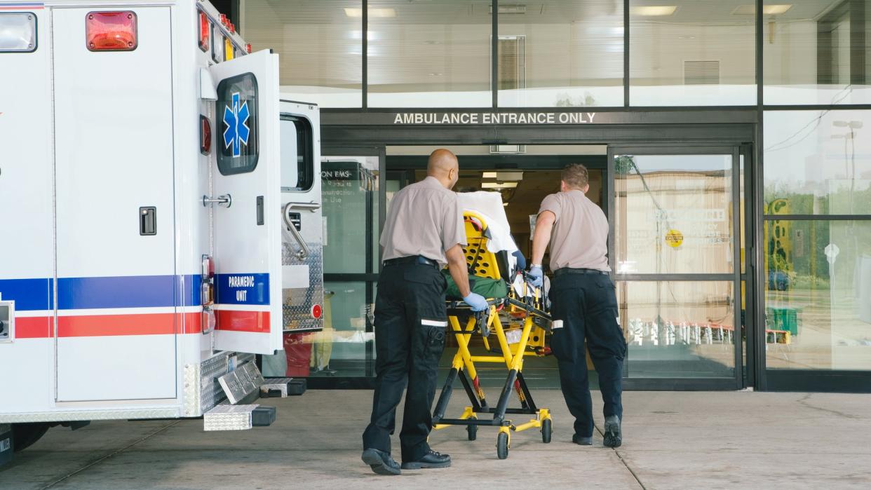 Paramedics taking patient on stretcher from ambulance to hospital.