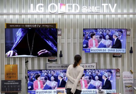 FILE PHOTO: A woman looks at LG Electronics' organic light-emitting diode (OLED) TV sets, which are made with LG Display flat screens, at its store in Seoul, South Korea, April 26, 2016. REUTERS/Kim Hong-Ji/File Photo