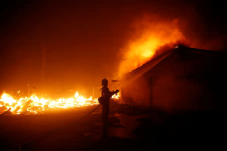 A firefighter battles the Woolsey Fire in Malibu, California, U.S. November 9, 2018. The fire destroyed dozens of structures, forced thousands of evacuations and closed a major freeway. REUTERS/Eric Thayer