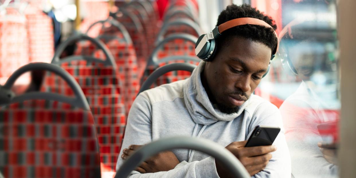 traveler on bus headphones looking at phone