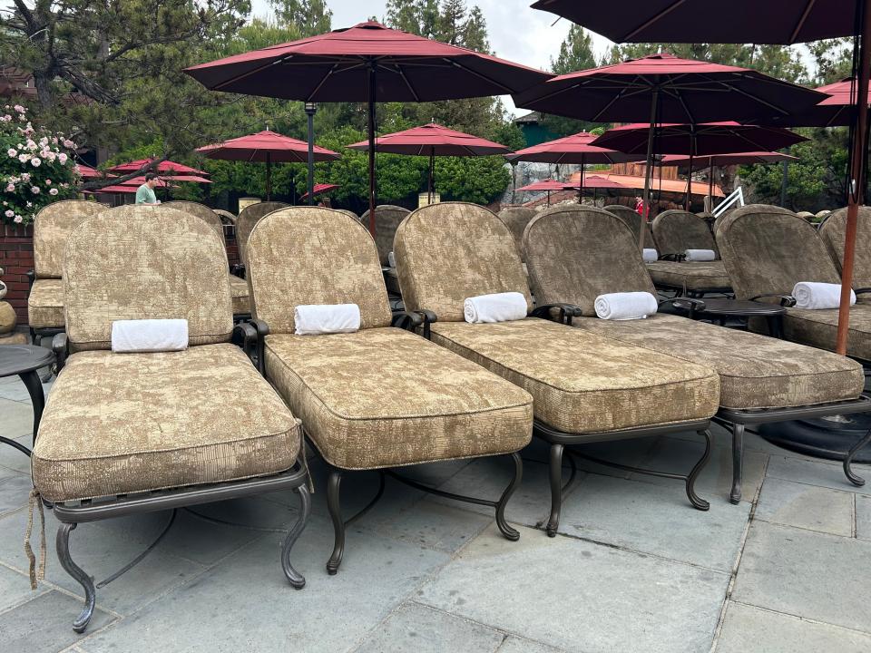 Plush lounge chairs with rolled-up white towels and red umbrellas.