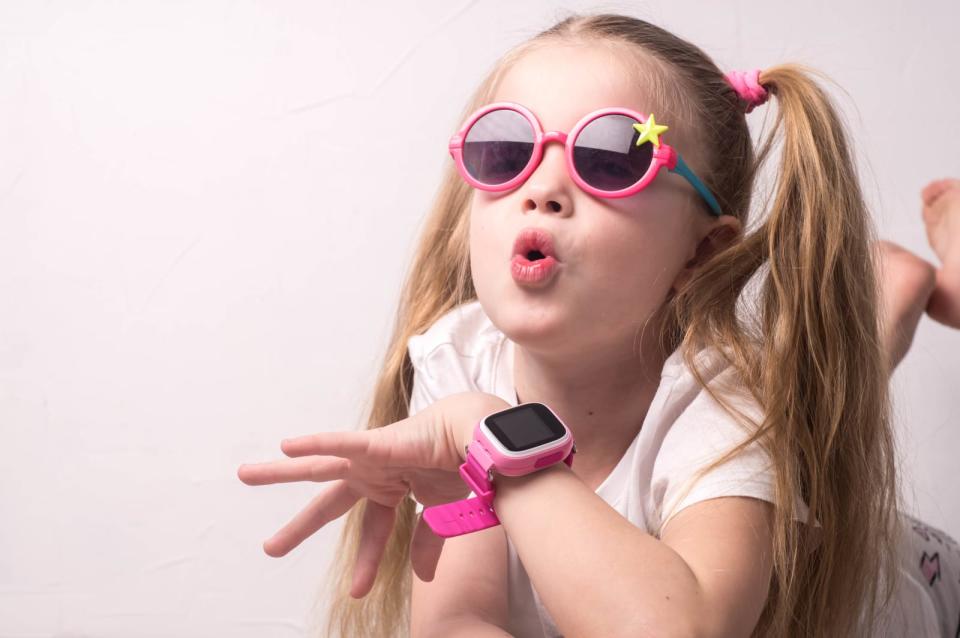 Technology for children: a girl wearing pink glasses uses a smartwatch.