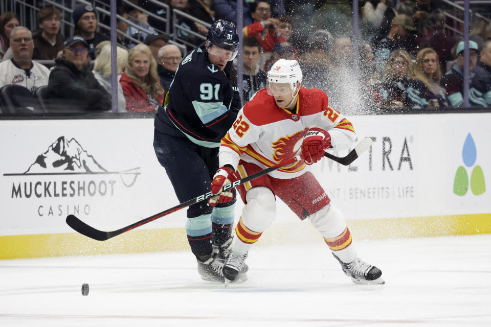 Calgary Flames center Trevor Lewis (22) skates to the puck, beating Seattle Kraken right wing Daniel Sprong (91) to it during the second period of an NHL hockey game Friday, Jan. 27, 2023, in Seattle. (AP Photo/John Froschauer)