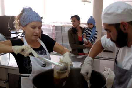 A woman carries her child as she waits for a cup of soup being served by chefs of La Casa Bistro restaurant, members of the "Full Stomach, Happy Heart" (Barriga llena, corazon contento) charity, at the J.M. de los Rios Children Hospital in Caracas, Venezuela February 13, 2017. REUTERS/Marco Bello