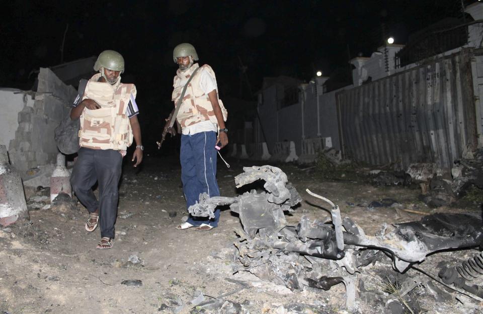 Somali police officers assess the scene of an explosion outside the Jazira hotel in Mogadishu