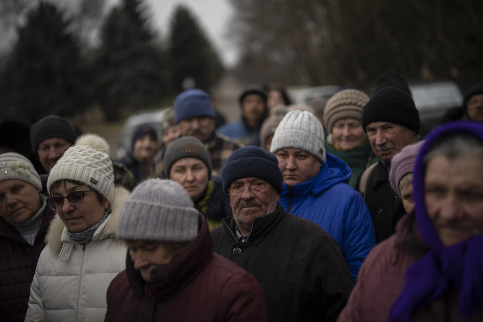 Residents gather around aid workers in Kalynivske, a village that was hit by shelling last fall in Ukraine, Saturday, Jan. 28, 2023. (AP Photo/Daniel Cole)