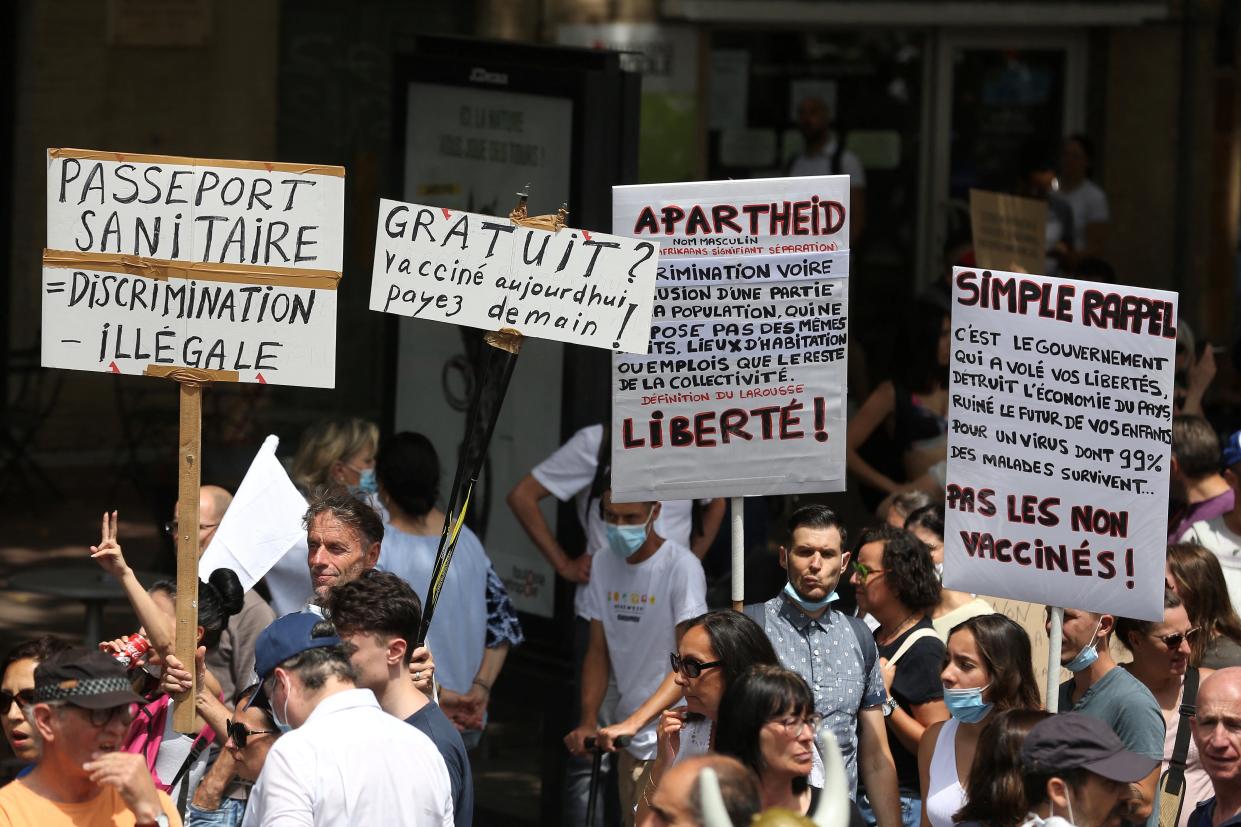 Demonstrators hold up placards and banners, which read as 'Health Passport = Illegal Discrimination; Vaccine, Free today, but pay tomorrow; Apartheid, Freedom; Simple Reminder - no to vaccines' during a protest against the vaccination and the compulsory health pass called for by the French government, in Toulouse, southwestern France, on July 24, 2021. - Since July 21, people wanting to go to in most public spaces in France have to show a proof of Covid-19 vaccination or a negative test, as the country braces for a feared spike in cases from the highly transmissible Covid-19 Delta variant. (Photo by Fred SCHEIBER / AFP) (Photo by FRED SCHEIBER/AFP via Getty Images)