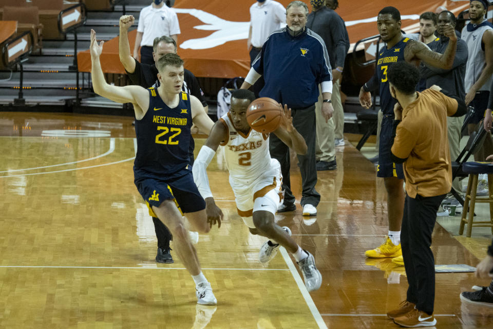 Texas guard Matt Coleman, III (2) is fouled by West Virginia guard Sean McNeil (22) at the end of the second half of an NCAA college basketball game, Saturday, Feb. 20, 2021, in Austin, Texas. (AP Photo/Michael Thomas)