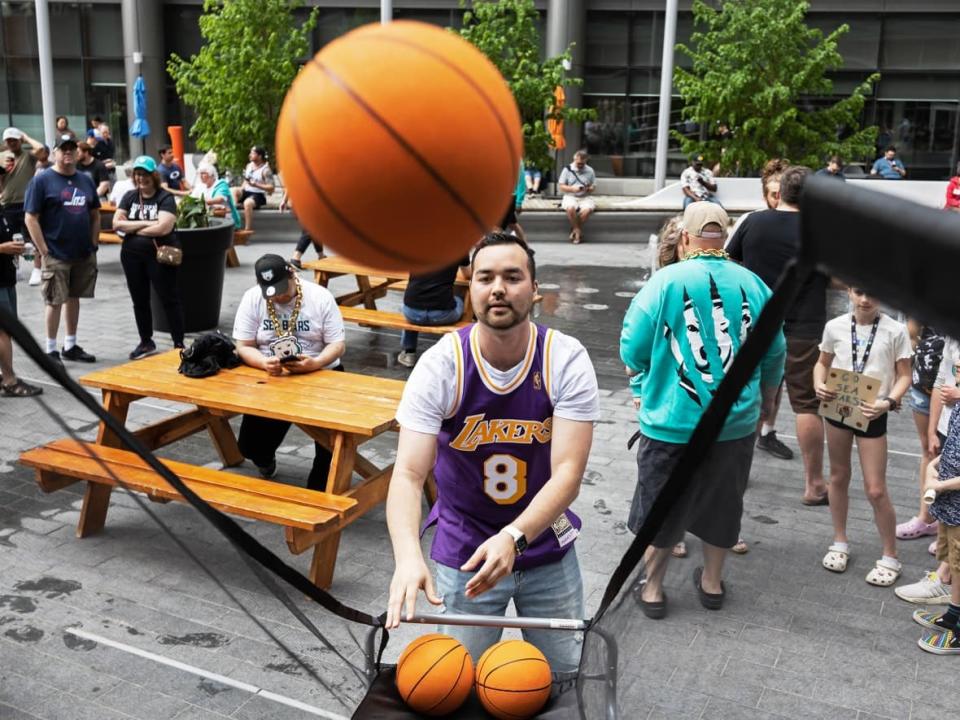 A man shoots hoops during a pre-game party in True North Square Saturday afternoon, ahead of the Winnipeg Sea Bears match against the Vancouver Bandits.  (Prabhjot Singh Lotey/CBC - image credit)