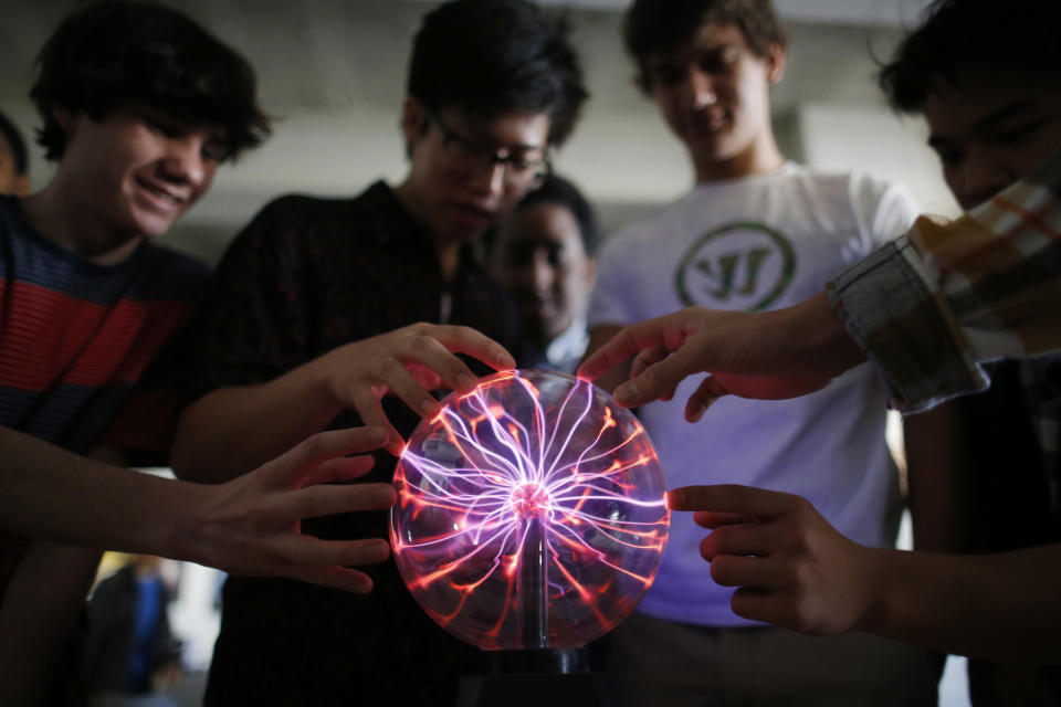 Students Niko Bartash, 11th grade, left; Ulysses Campbell, 12th grade, second left; and Max Cooper, 11th grade, second right; touch a plasma globe in the Advanced Placement Physics class at Woodrow Wilson High School in Washington, Friday, Feb. 7, 2014. The College Board says in a new report that the number of U.S. public students taking Advanced Placement classes doubled over the last decade. The class of 2013 of took 3.2 million AP exams. (AP Photo/Charles Dharapak)