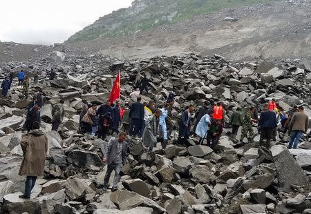 People search for survivors at the site of a landslide that destroyed some 40 households, where more than 100 people are feared to be buried, according to local media reports, in Xinmo Village, China June 24, 2017. REUTERS/Stringer