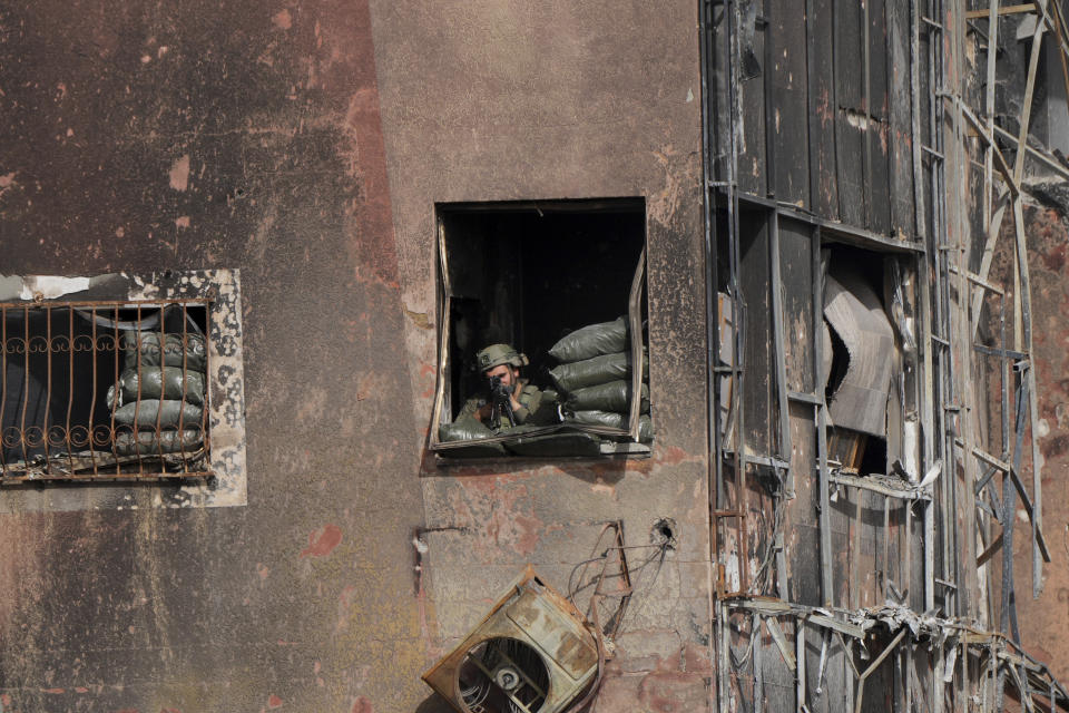 An Israeli soldier looks at Palestinians fleeing south at Salah al-Din road in central Gaza Strip on Sunday, Nov. 26, 2023, on the third day of a temporary cease-fire between Hamas and Israel. (AP Photo/Hatem Moussa)