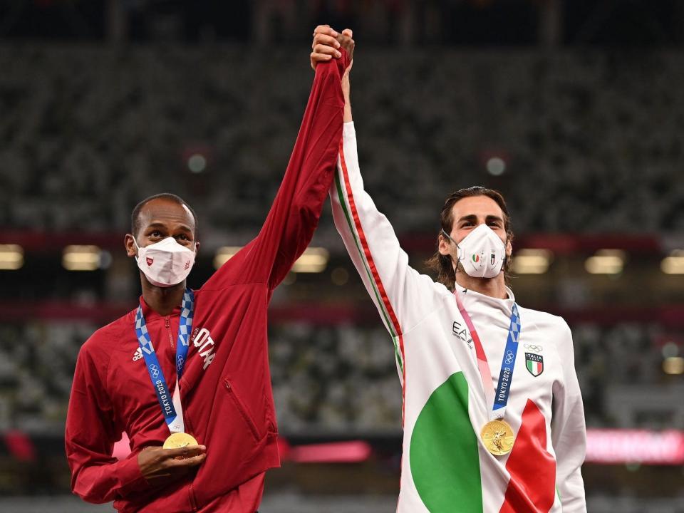 Qatar's Mutaz Essa Barshim and Italy's Gianmarco Tamberi hold hands while sharing a joint gold medal in the high jump.