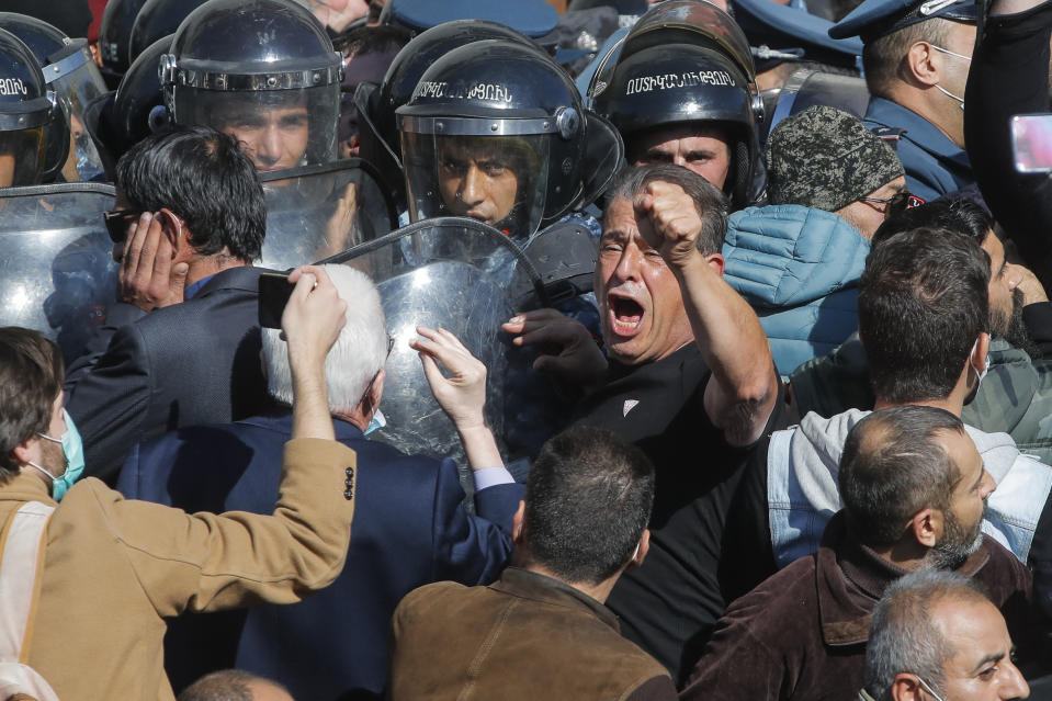 People argue with police during a protest against an agreement to halt fighting over the Nagorno-Karabakh region, in Freedom Square in Yerevan, Armenia, Wednesday, Nov. 11, 2020. Thousands of people flooded the streets of Yerevan once again on Wednesday, protesting an agreement between Armenia and Azerbaijan to halt the fighting over Nagorno-Karabakh, which calls for deployment of nearly 2,000 Russian peacekeepers and territorial concessions. Protesters clashed with police, and scores have been detained. (AP Photo/Dmitri Lovetsky)