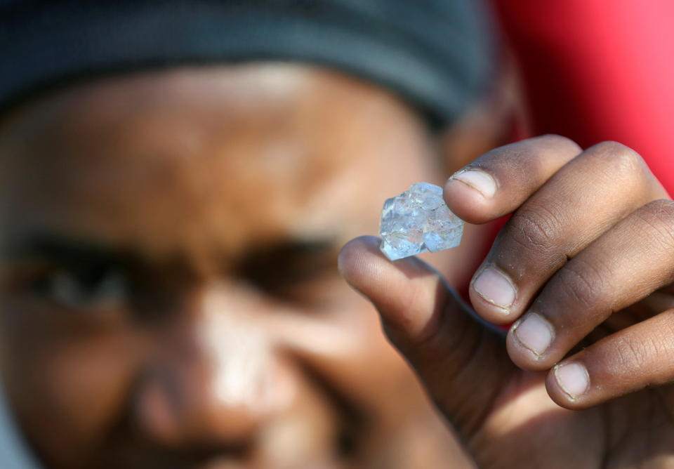 A man shows an unidentified stone as fortune seekers flock to the village after pictures and videos were shared on social media showing people celebrating after finding what they believe to be diamonds, in the village of KwaHlathi outside Ladysmith, in KwaZulu-Natal province, South Africa, June 14, 2021. REUTERS/Siphiwe Sibeko     TPX IMAGES OF THE DAY