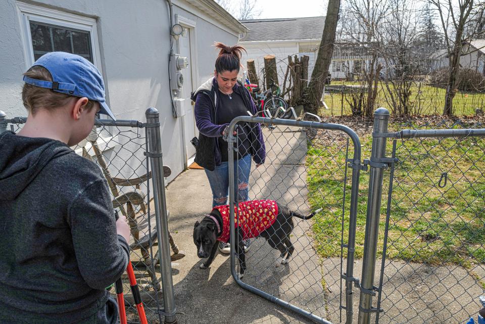 Ashley Graham and her dog, Zoey, greet Sam Bliss, 11, as he shows up to clean her backyard of dog poop Saturday, March 2, 2024. Sam is in his third year of his dog waste disposal business.