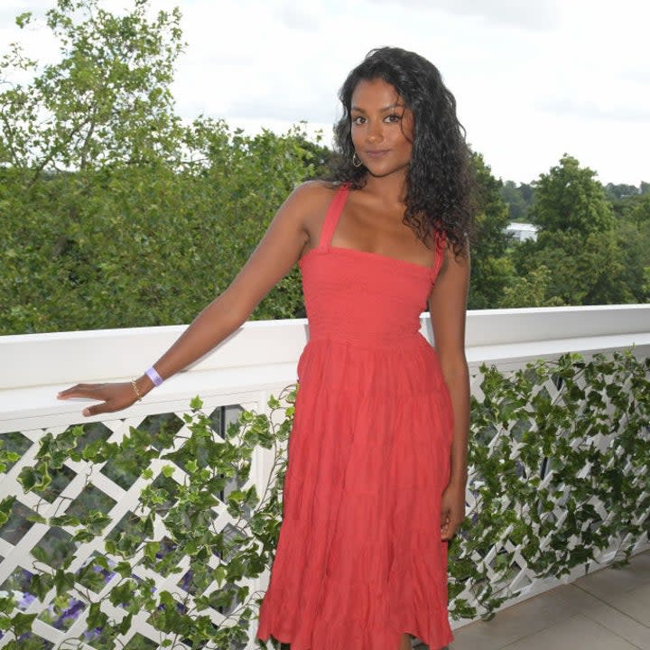 Simone Ashley poses for a photo in a summer dress and cowboy boots