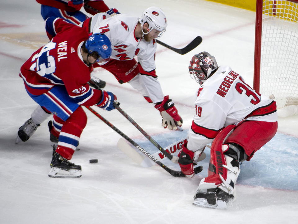 Carolina Hurricanes defenseman Jaccob Slavin (74) helps to clear the crease as teammate Alex Nedeljkovic (39) puts the stop on Montreal Canadiens center Jordan Weal (43) during the second period of an NHL hockey game Saturday, Feb. 29, 2020, in Montreal. (Peter McCabe/The Canadian Press via AP)