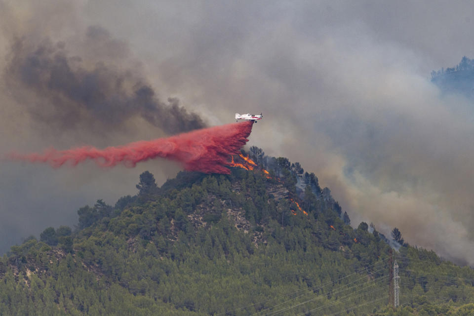 A firefighting plane drops retardant on a forest fire in the Castellgali area of Catalonia, Spain on Sunday July 17, 2022. Firefighters battled wildfires raging out of control in Spain and France as Europe wilted under an unusually extreme heat wave that authorities in Madrid blamed for hundreds of deaths. (Lorena Sopena/Europa Press via AP)