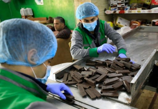 Workers at al-Arees sweets factory in Gaza City sort a batch of chocolate-covered biscuits