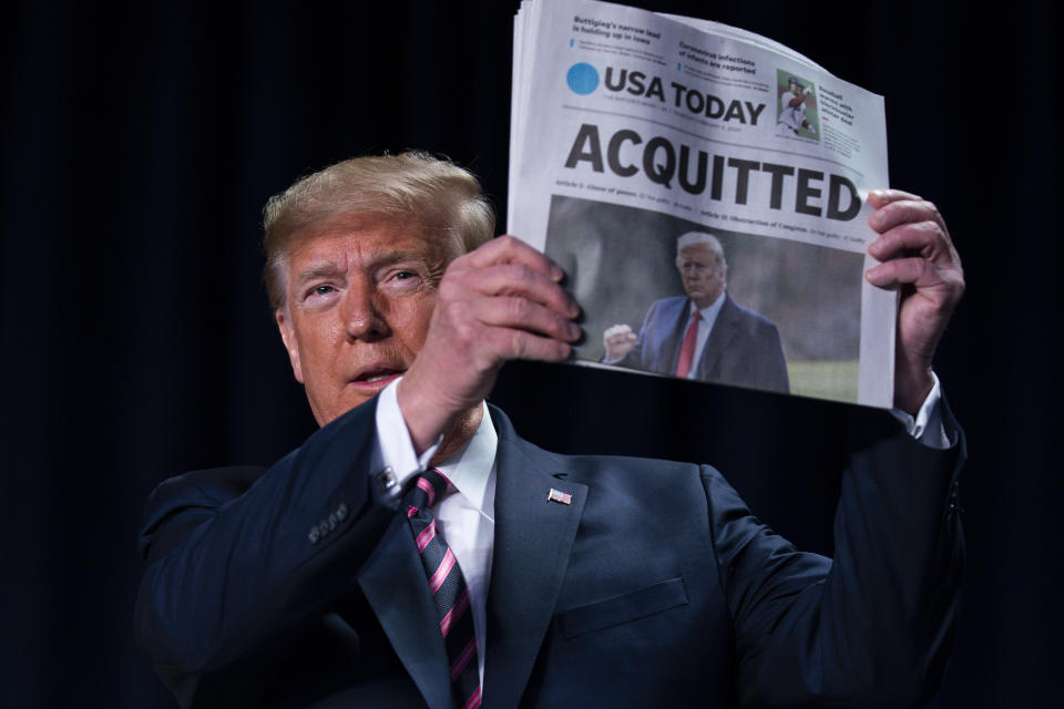 President Trump holds up a newspaper with the headline that reads "ACQUITTED" during the 68th annual National Prayer Breakfast at the Washington Hilton on Thursday. (AP Photo/ Evan Vucci) 