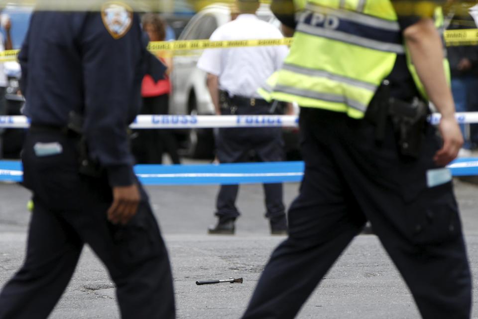 A hammer lies on ground at a crime scene as members of NYPD police stand by at intersection of 37th street and 8th avenue in midtown Manhattan in New York