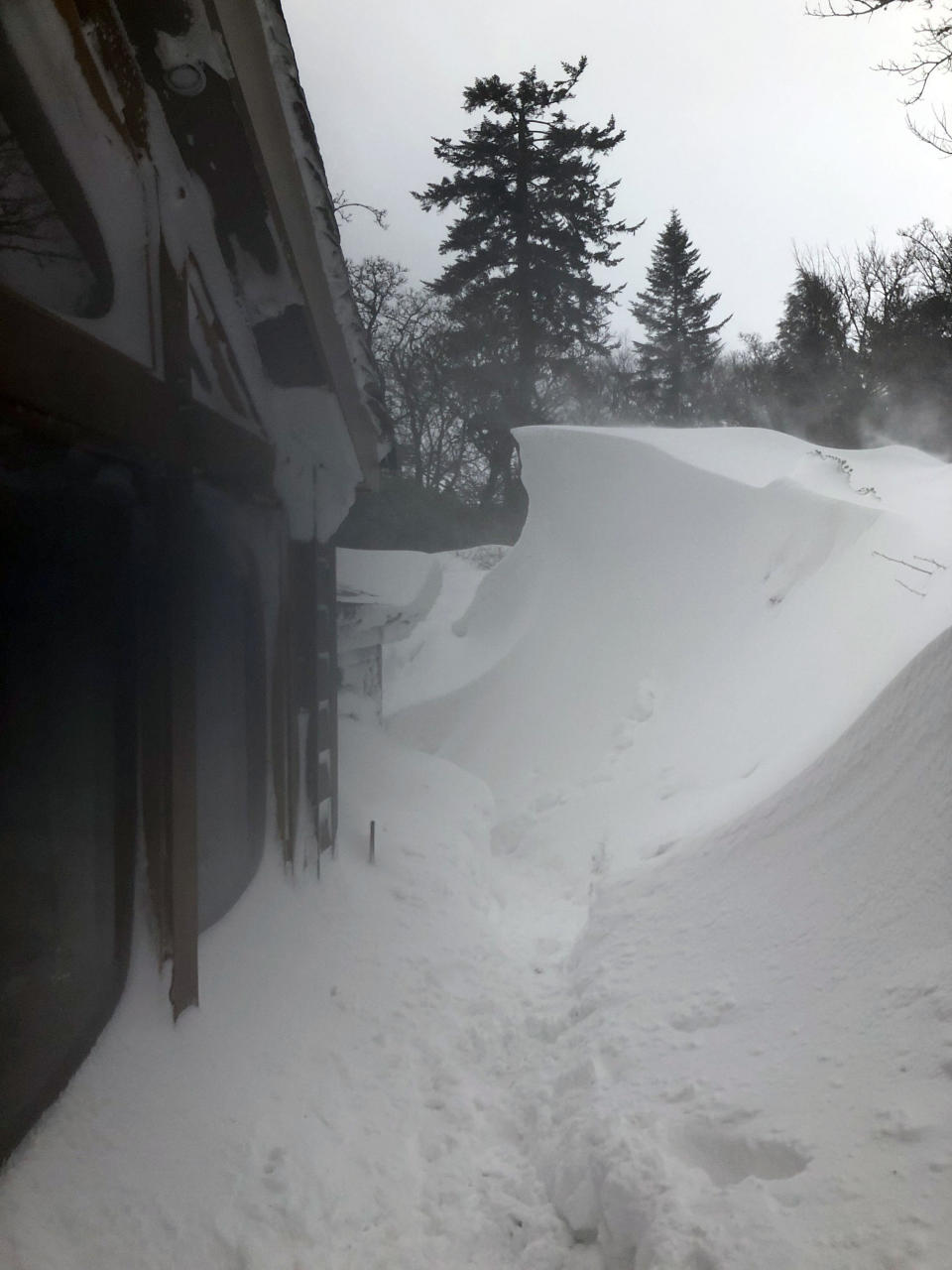 <em>Buried – an elderly couple’s house was being buried in snow drifts up to 12ft (Pictures: PA)</em>