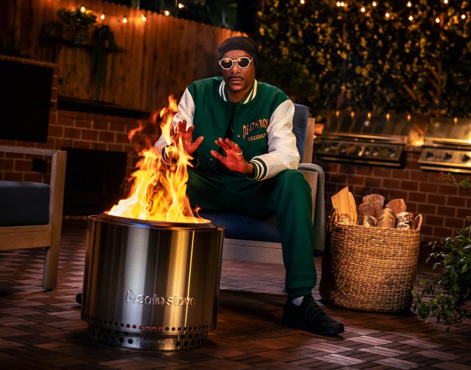 Snoop Dogg lights up, without smoke, as he warms his hands over a Solo Stove fire pit.