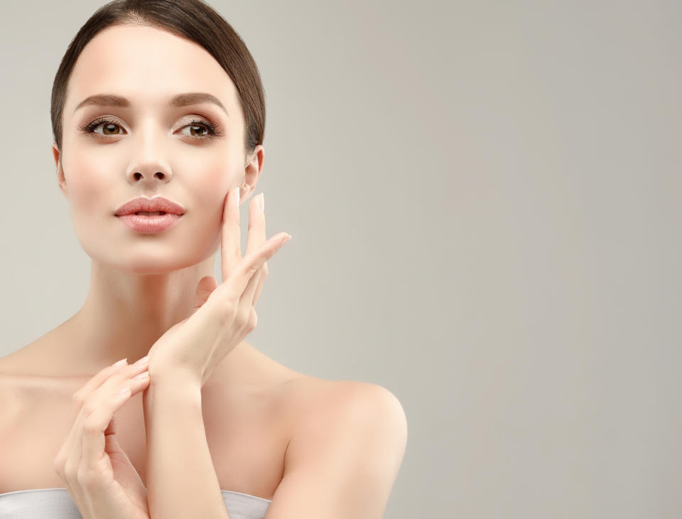 A woman touching her face as if applying makeup.