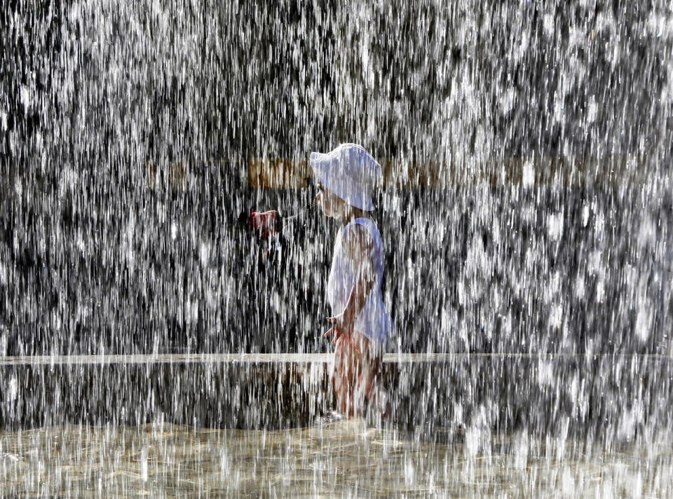 A small child plays at a fountain in front of the Old Opera in Frankfurt