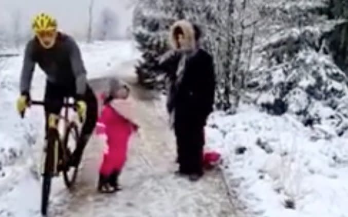 Cyclist sticking his knee out as he rides past the girl