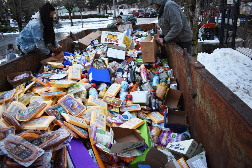 People salvage food from a dumpster outside a Fred Meyer's location in Portland, Ore., on Feb. 16, 2021, after it had been thrown out during a power outage following a storm. (J.L. Simonis via Twitter)
