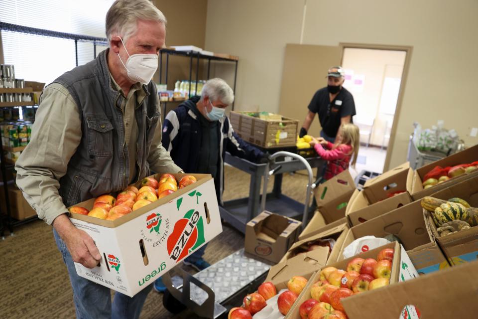 Aware Food Bank employee Mike Regan shelves apples at Aware Food Bank.