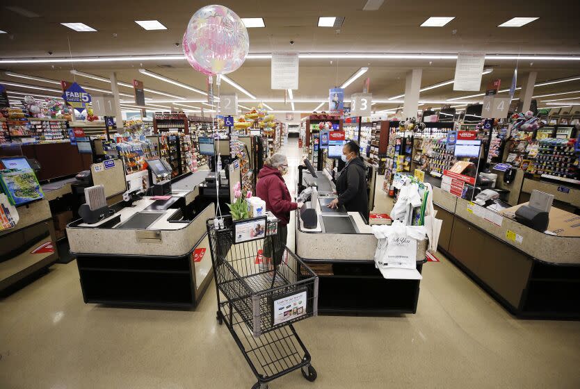 TORRANCE, CA - APRIL 27: Vons checker cashier Miyoshi Lampkin who has worked at Vons for 40 years checks out shopper Jeane Byers who was first to checkout at the Vons located at 24325 Crenshaw Blvd in Torrance after doors opened at 6 a.m. for seniors and at-risk shoppers due to the Coronavirus. Most of the team arrives at 5 a.m. to stock the shelves with product, sanitize the location for staff and shoppers, and picker/shoppers begin to collect items for .com home delivery shoppers. Vendors arriving throughout the morning must read a checklist of warnings, sign in and they must wear face covering. Vons on Monday, April 27, 2020 in Torrance, CA. (Al Seib / Los Angeles Times)