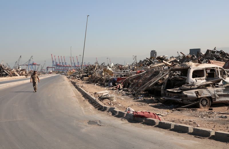 A Lebanese army soldier walks past debris and damaged vehicles at Beirut port