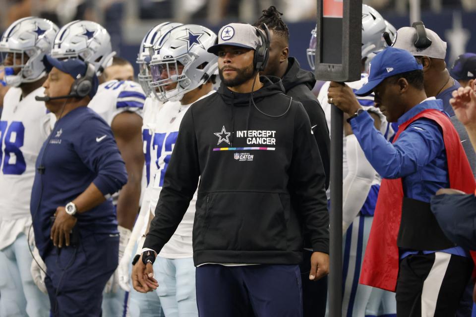 Dallas Cowboys quarterback Dak Prescott, center, watches play in the second half of a NFL football game against the Washington Commanders in Arlington, Texas, Sunday, Oct. 2, 2022. (AP Photo/Ron Jenkins)