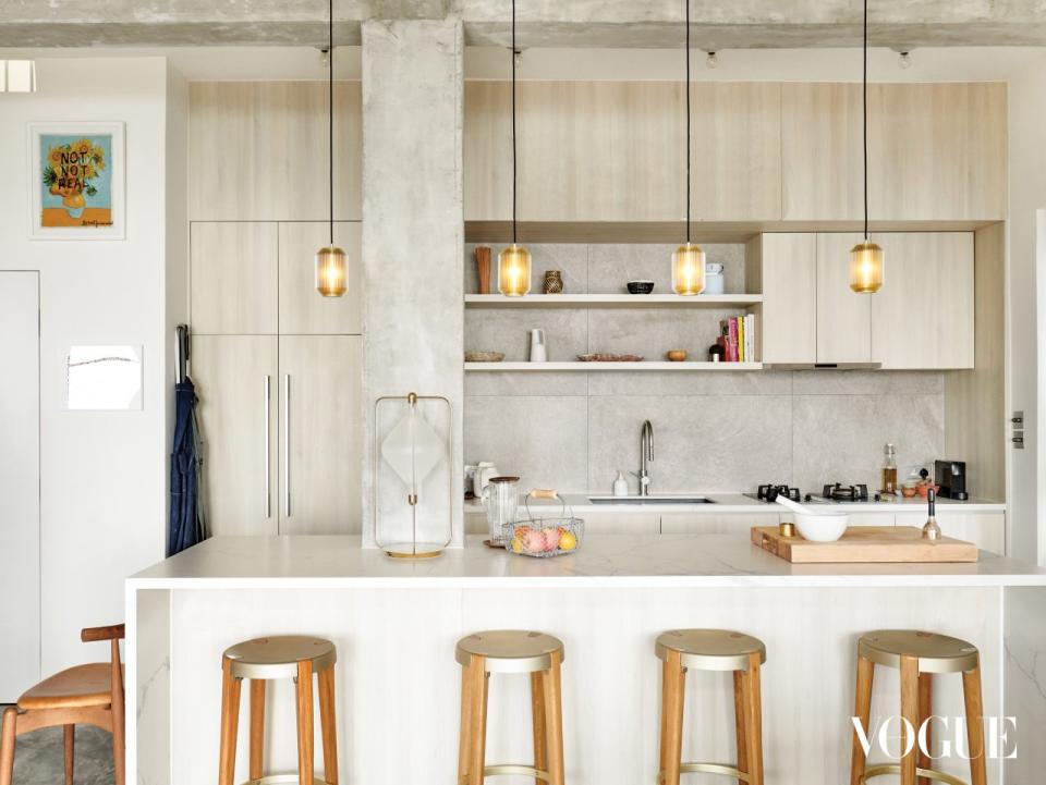  A sleek kitchen island is fitted with Otto Stools by Michael Young Home from Manks, while Joseph Lights for Michael Young by Michael Young light up the space above the kitchen counter. 