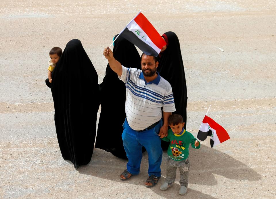 <p>An Iraqi man and a child wave the national flag in the central holy city of Najaf on May 12, 2018 as the country votes in the first parliamentary election since declaring victory over the Islamic State (IS) group. (Photo: Haidar Hamdani/ AFP/Getty Images) </p>