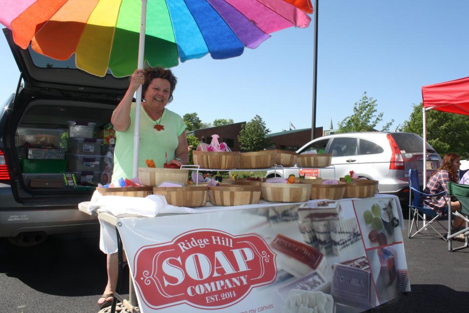 Vickie Fritzsche, of Ridge Hill Soap Company in Highland Heights, sets out her soaps under a multi-color umbrella at Campbell County Farmers Market in Highland Heights.