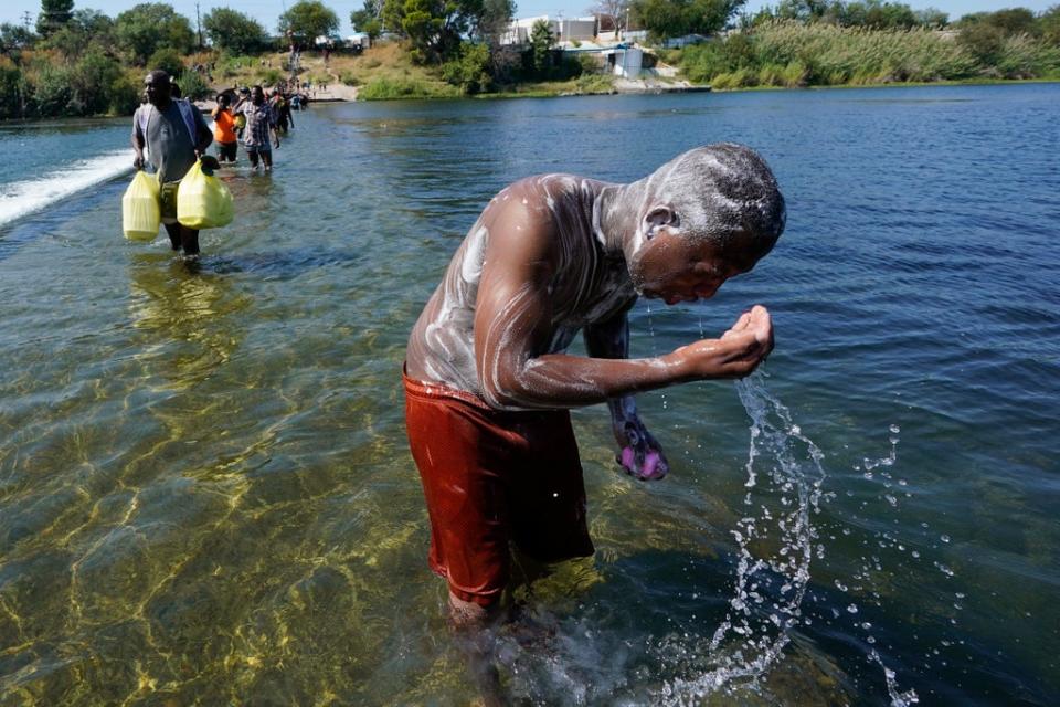 A Haitian migrant uses the Rio Grande to take a bath after crossing a dam from Mexico to the United States, Friday, 17 September 2021, in Del Rio, Texas (AP)