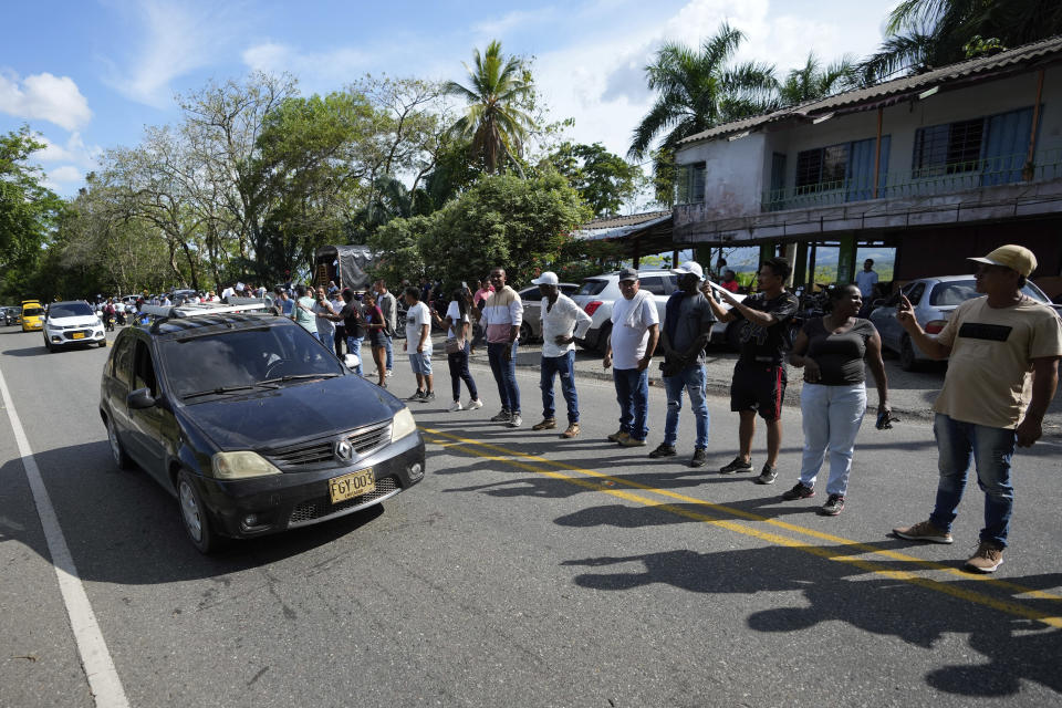 Mineros reciben a los vehículos que viajan de Caucacia a Medellín, permitiéndoles el paso seguro a través de Cáceres, Colombia, donde está el paro minero, el martes 14 de marzo de 2023. Durante más de 10 días, mineros informales que trabajan en la minería ilegal de oro han bloqueado carreteras, impidiendo el paso de vehículos y el transporte de alimentos en varias zonas de Antioquia, para protestar contra la destrucción, por orden del gobierno, de maquinaria que se utiliza en la búsqueda de oro. (AP Foto/Fernando Vergara)