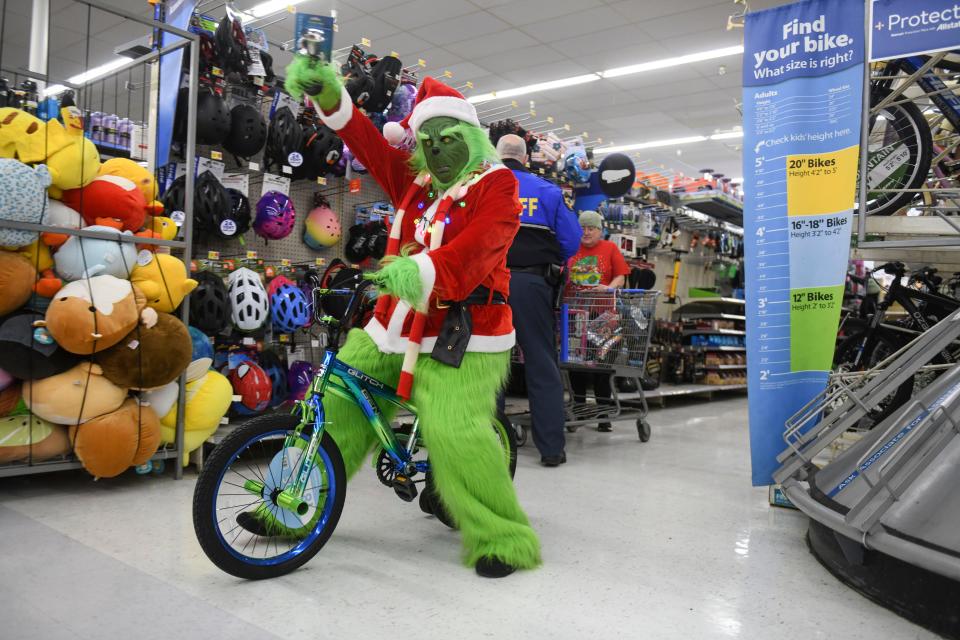 The Grinch rides a bicycle during the Columbia County Sheriff's Office Day with a Deputy at Walmart on Thursday, Dec. 21, 2023.