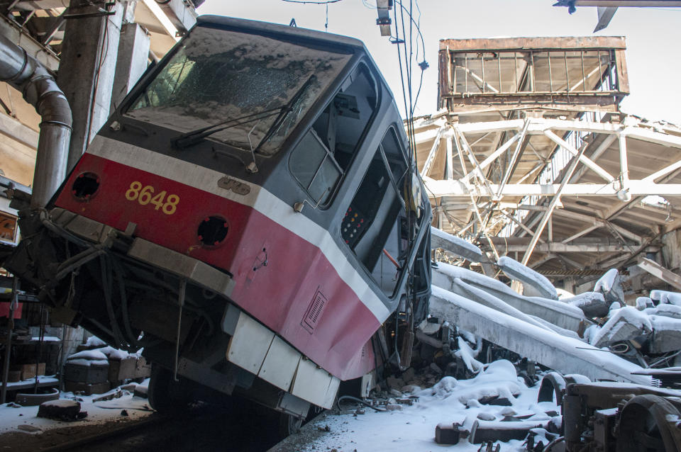 A tram that was upended by shelling, surrounded by debris. 