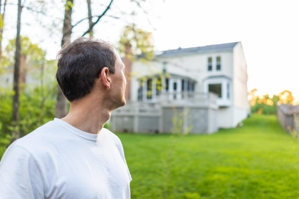 Young man homeowner in Herndon, Northern Virginia, Fairfax county residential neighborhood in spring or summer looking at house backyard