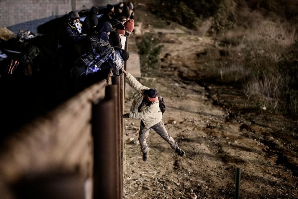 A migrant jumps the border fence to get into the U.S.