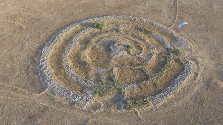 A general aerial view shows a prehistoric stone monument, known as Rujm el-Hiri in Arabic, meaning "stone heap of the wild cat", as a paraglider surfs above it in this July 24, 2014 picture. REUTERS/Chen Katz/Files