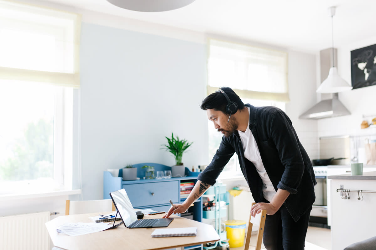 A man works from home while talking to a customer through a headset. 